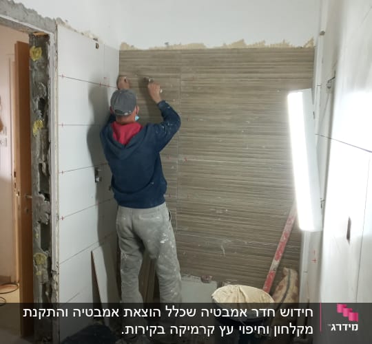 אדם מתקין אריחים על קיר בחדר שיפוצים